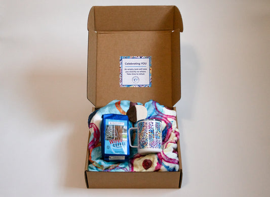 box with blanket, mug, coffee, and cookie