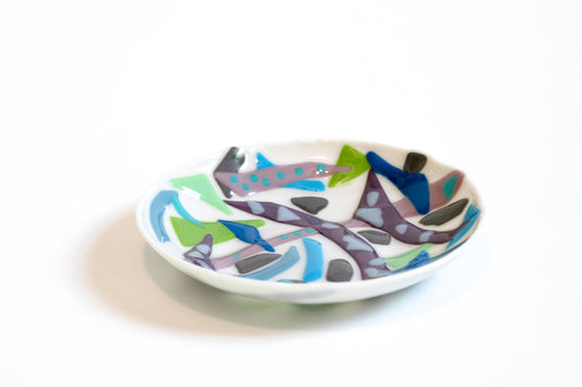 white glass shallow serving bowl with lines of purples and blues