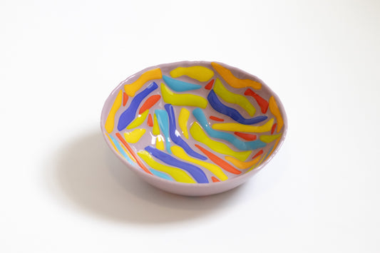 purple glass bowl with lines of yellow, green, blue and orange