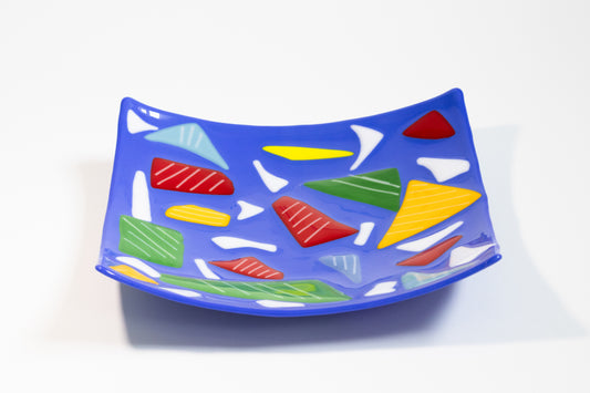 blue plate with large triangles of yellow, red, green with with smaller white shapes in between and lines on top