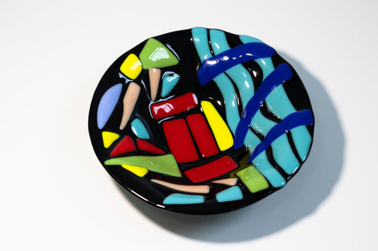 black bowl with blue wavey lines at the bottom and blocks of red, yellow, and green above it