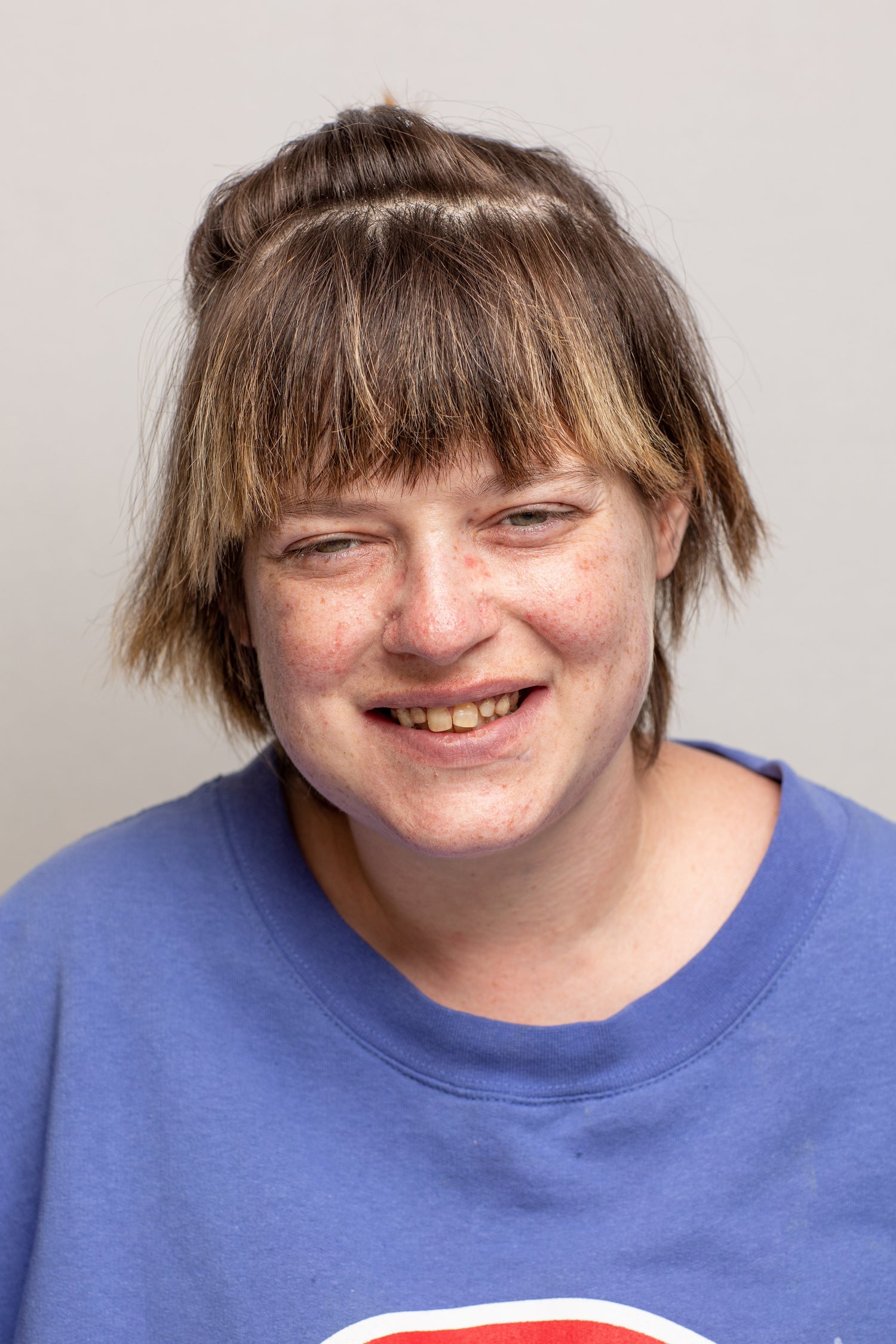 young woman with short hair smiling with blue shirt