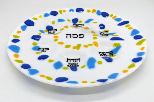 white seder plate with border of green, blue and yellow dots