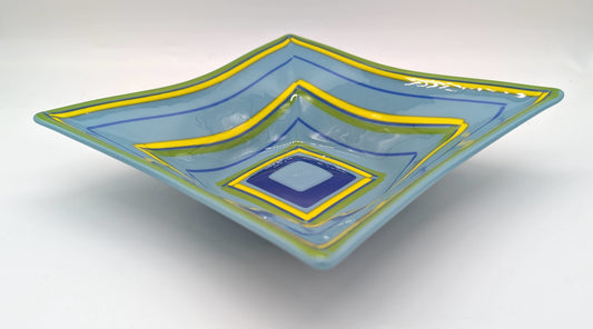 blue square bowl with alternating lines of green, blue, and yellow following the edge of the border and shrinking towards the center