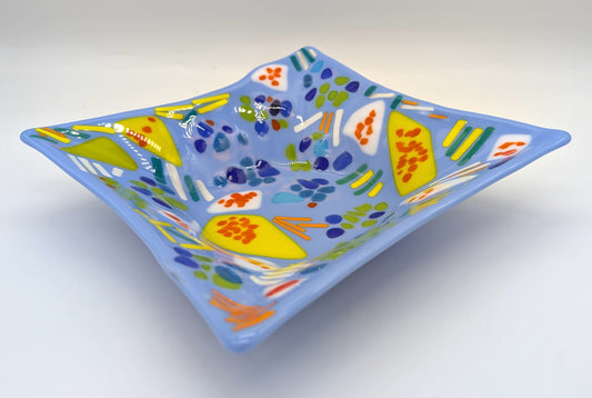 blue glass square bowl with yellow and white shapes with orange dots on top