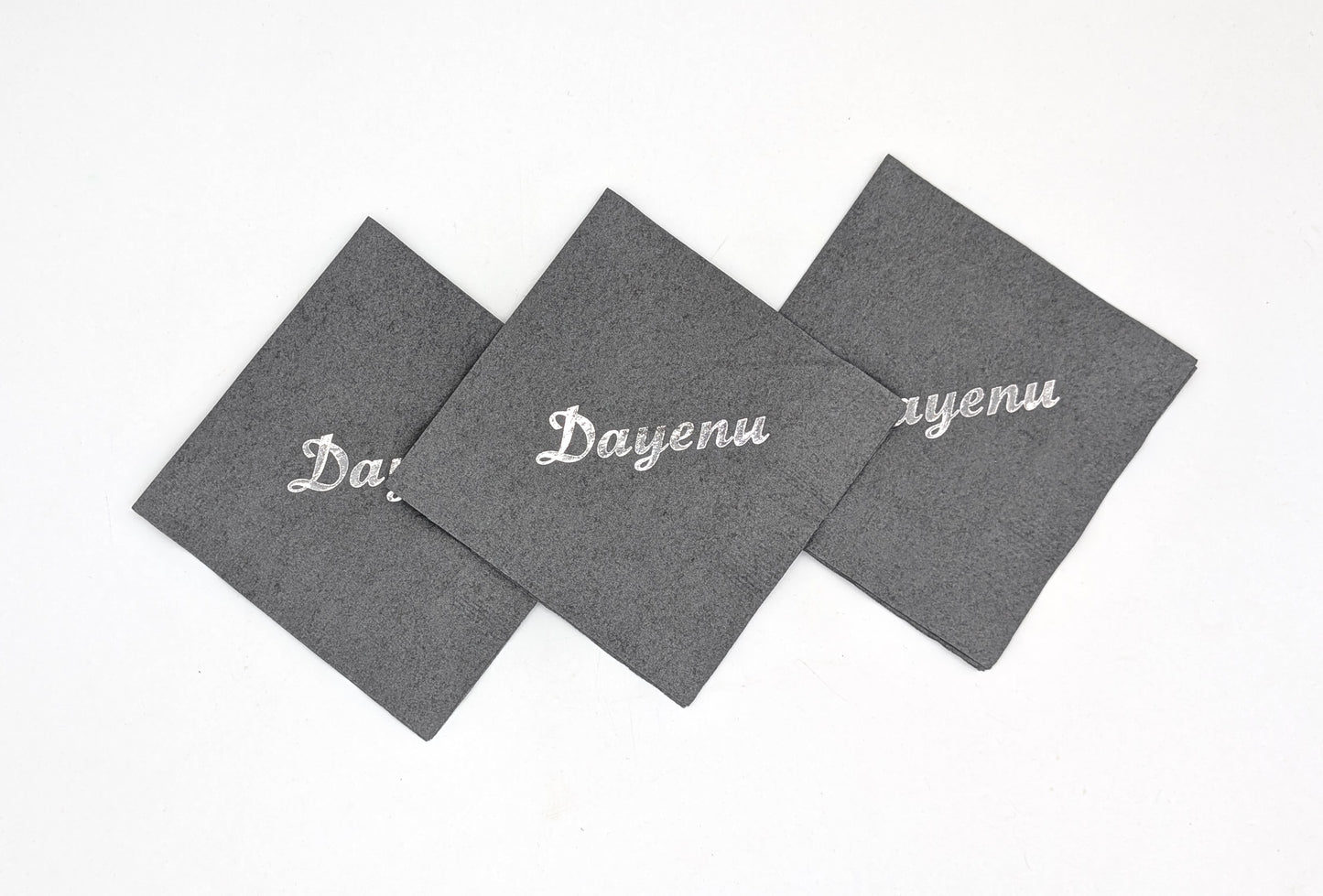 grouping of 3 gray napkins that say dayenu