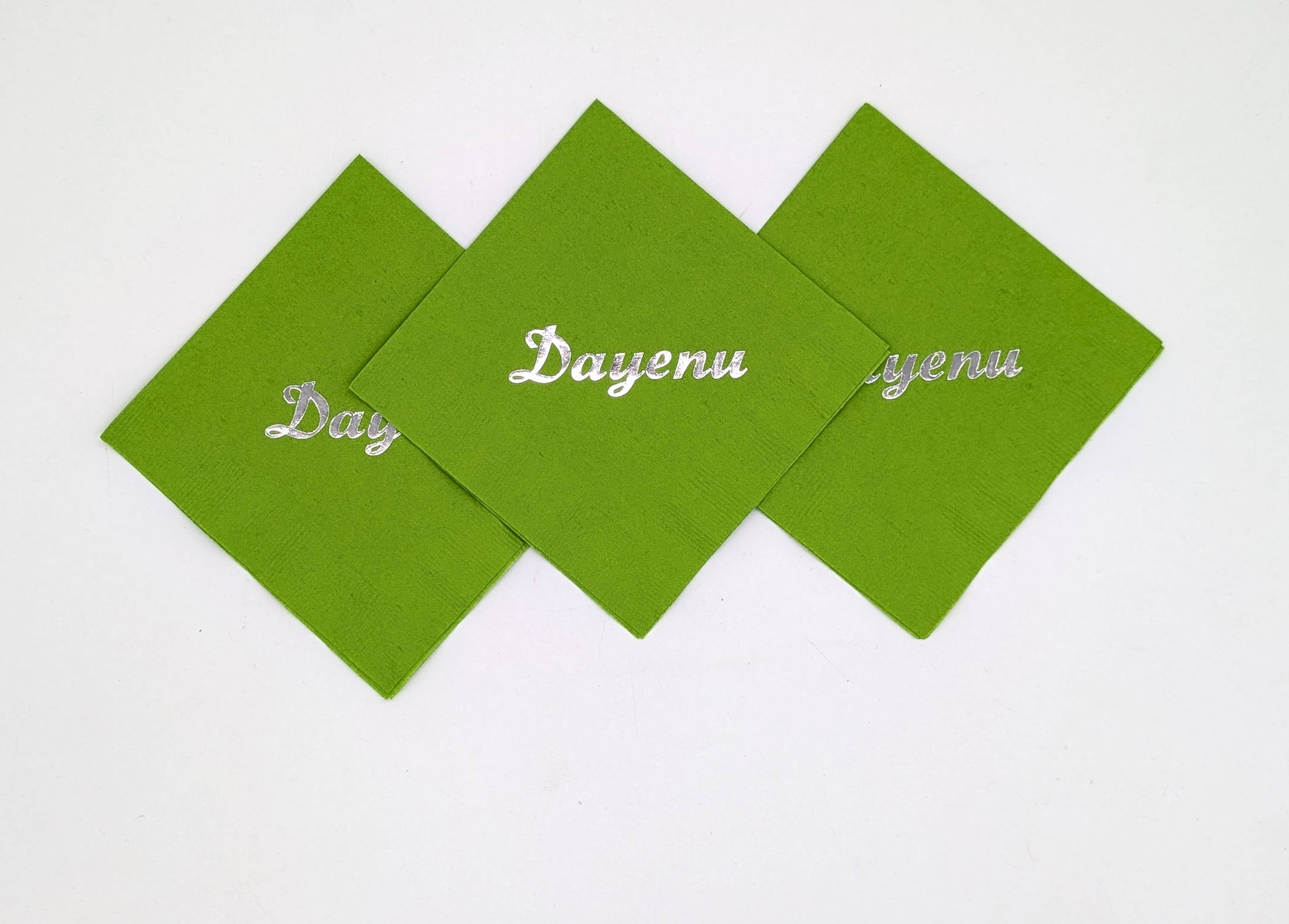 grouping of 3 lime napkins that say dayenu