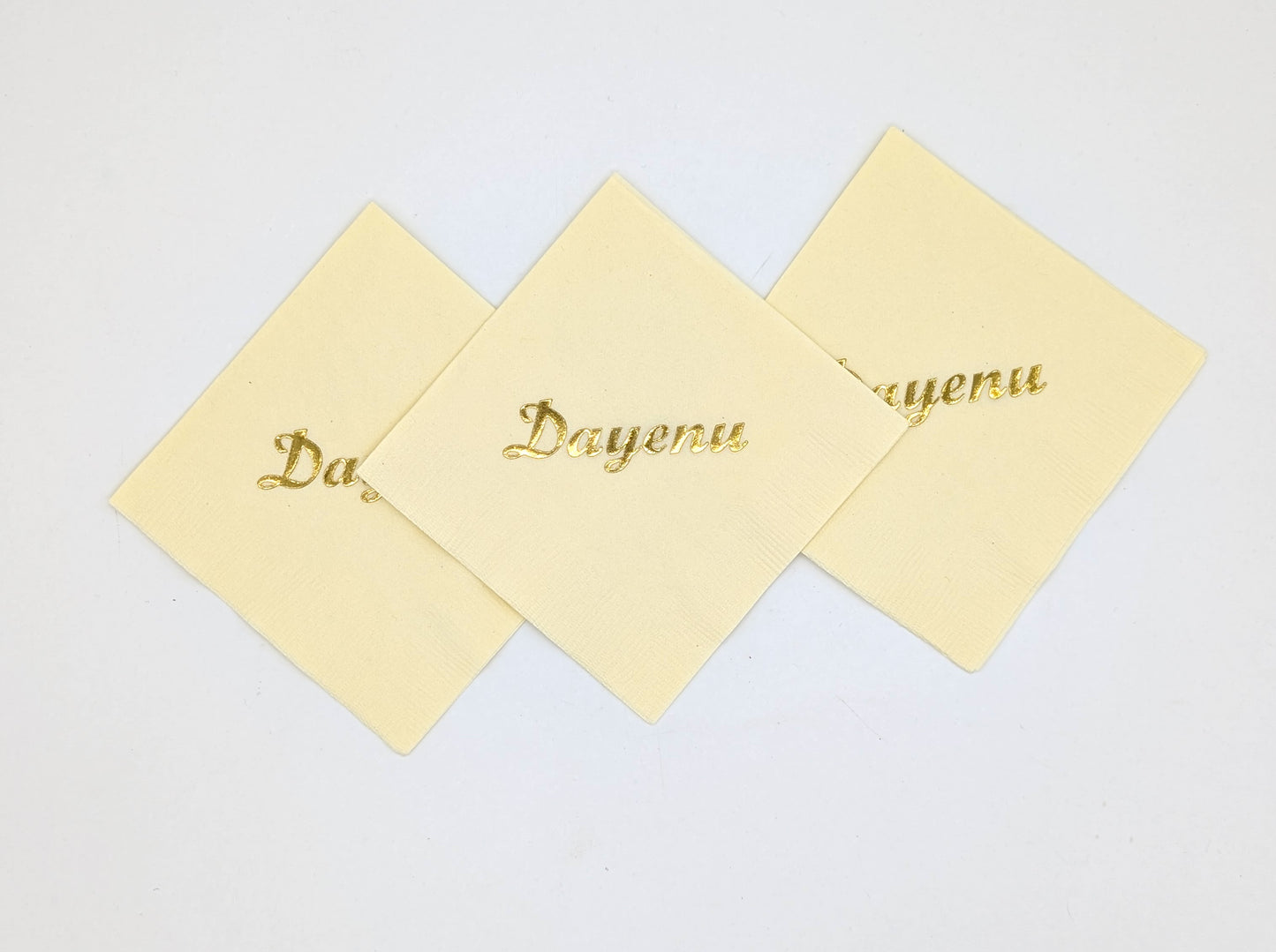 grouping of 3 cream napkins that say dayenu