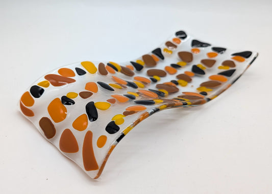 curved spoon rest with alternating colors of browns and yellow with black dots