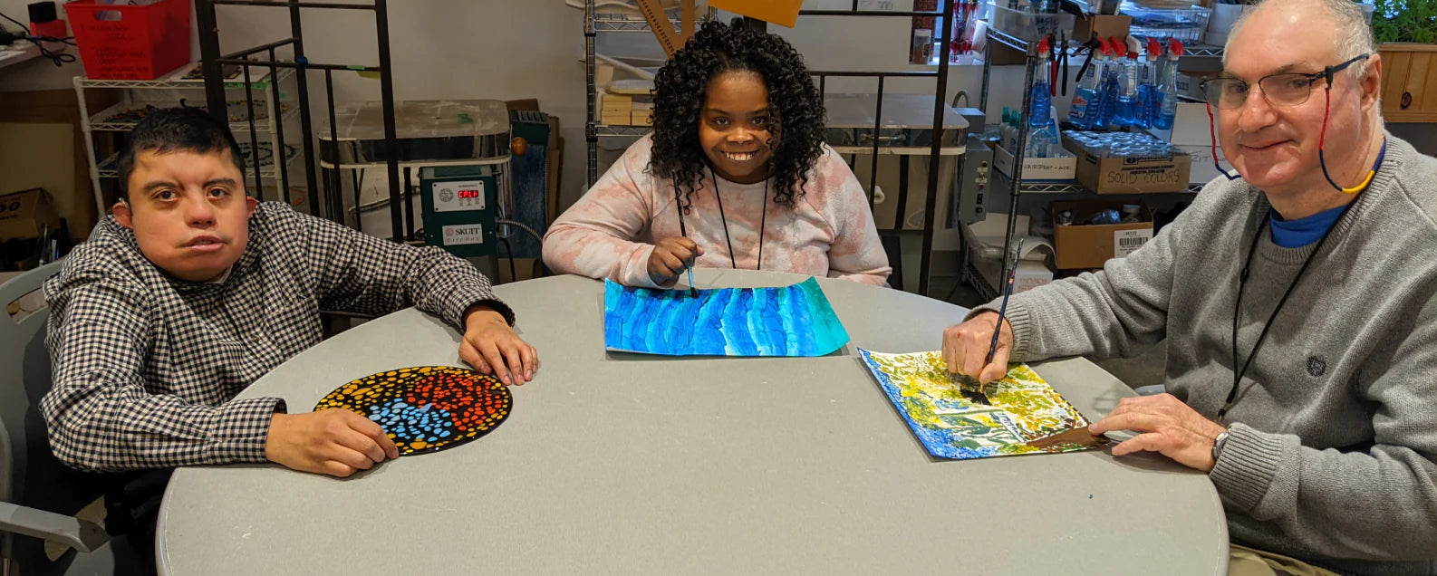 group of 3 artists working on fused glass art and paintings.