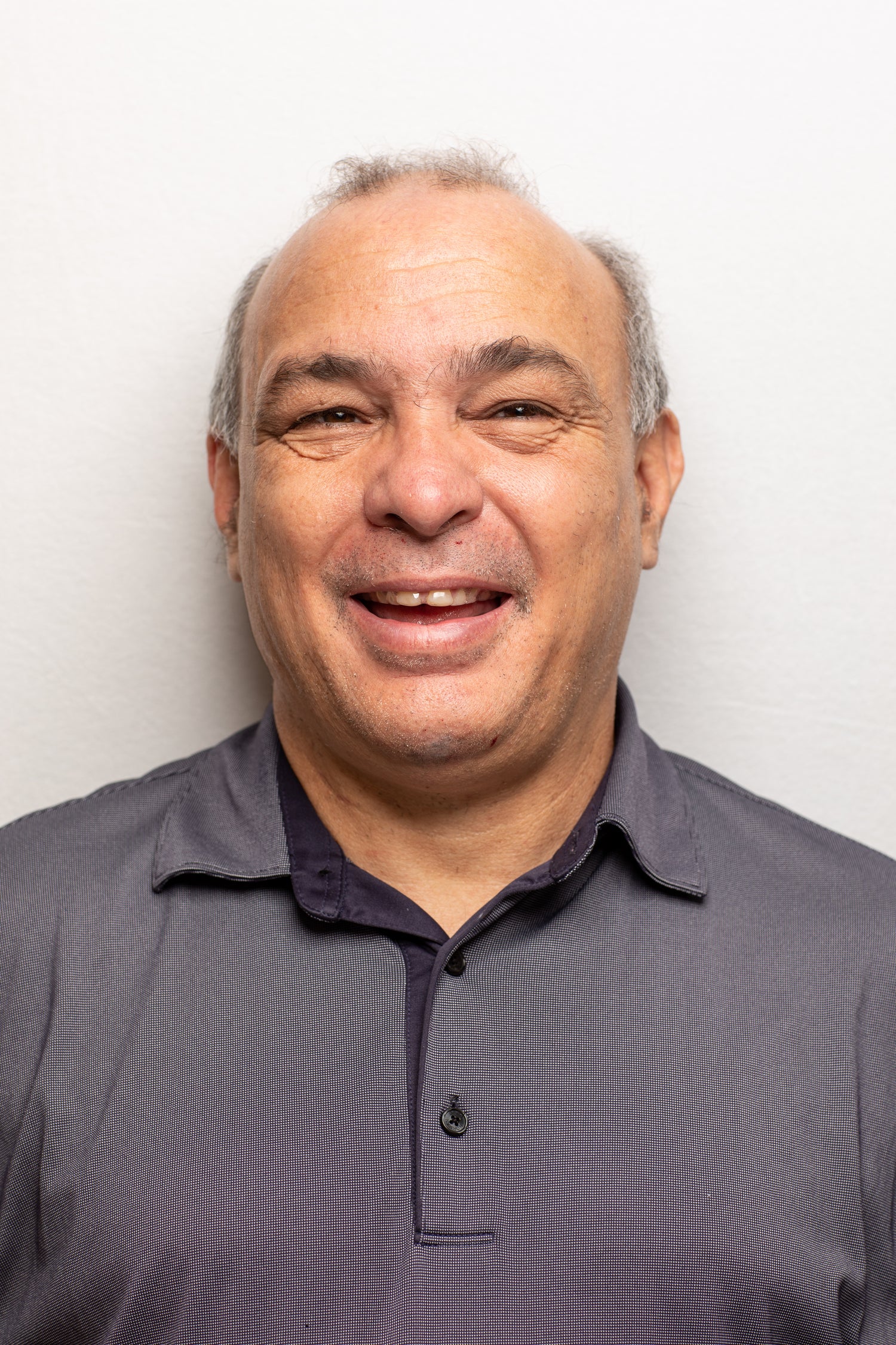 picture of a man with receding hair smiling wearing gray polo shirt