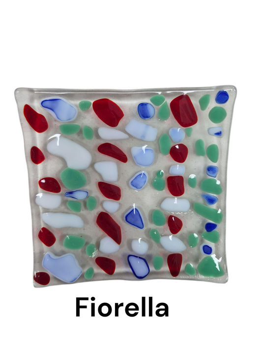 Handcrafted fused glass art tray, it displays a vibrant and rhythmic mosaic pattern featuring smooth, organic glass shapes in bold red, crisp white, teal, and touches of blue, all fused onto a translucent, frosted glass base.

Medium: Fused Glass

Size: Approximately 6" x 6"

Year: 2026