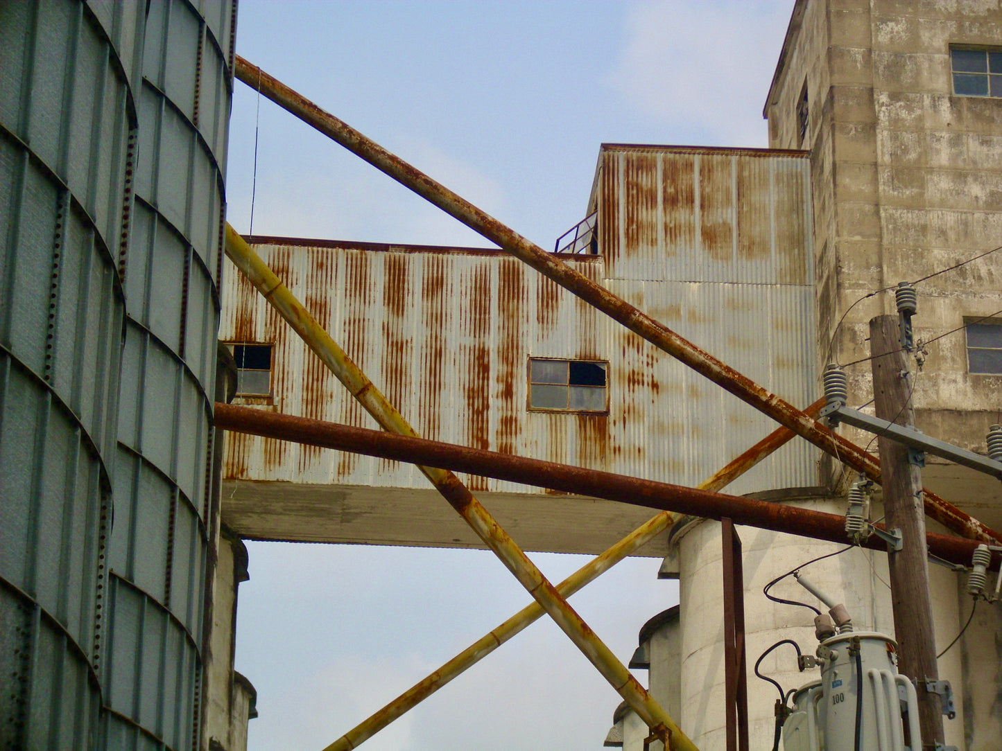 Artistic photography of rusted pipes, warehouse, and telephone pole