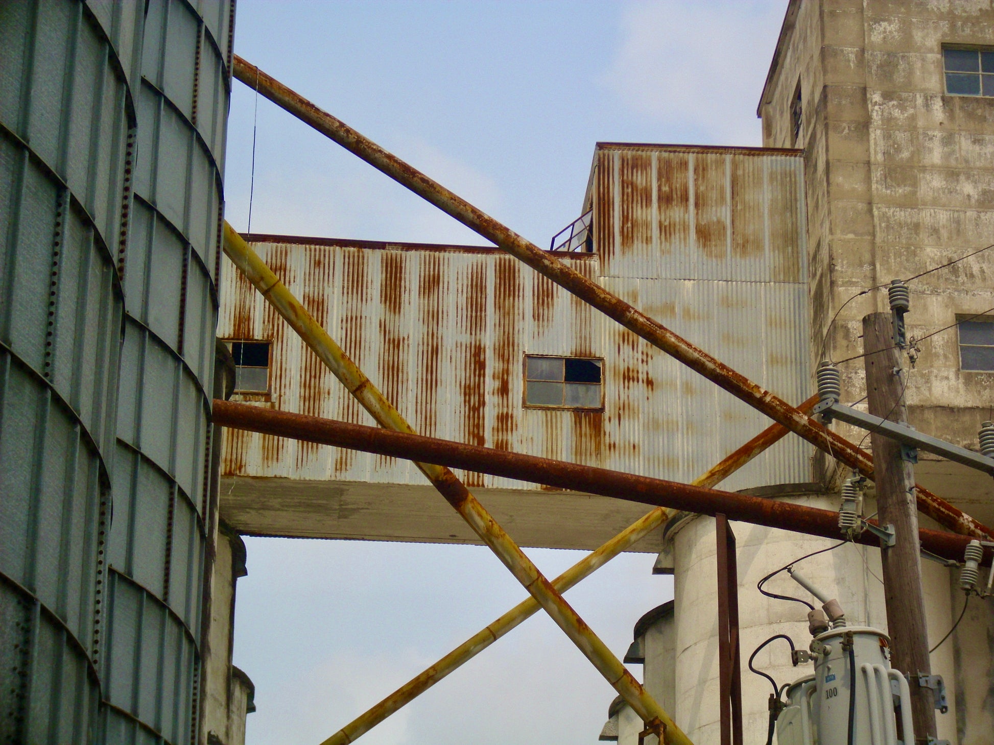 Artistic photography of rusted pipes, warehouse, and telephone pole