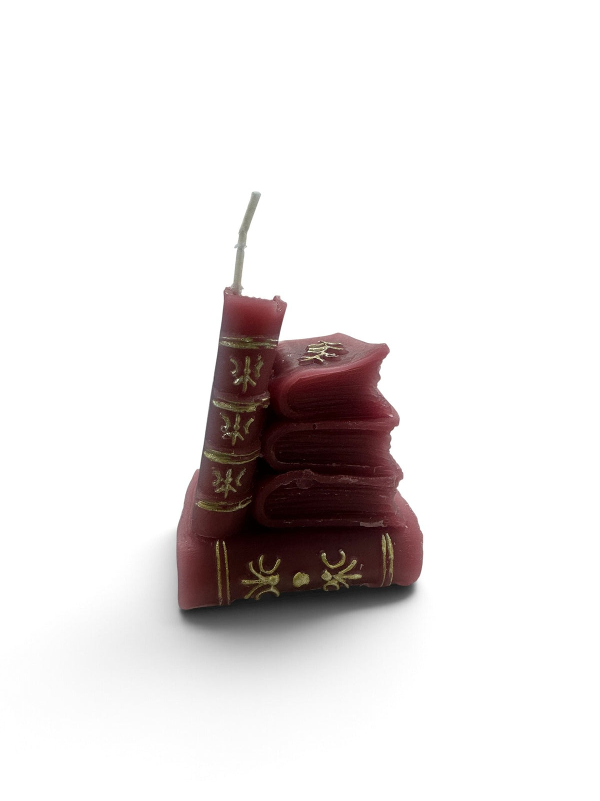 A miniature stack of marroon book candles with gold-detailed spines topped with an open book wick.