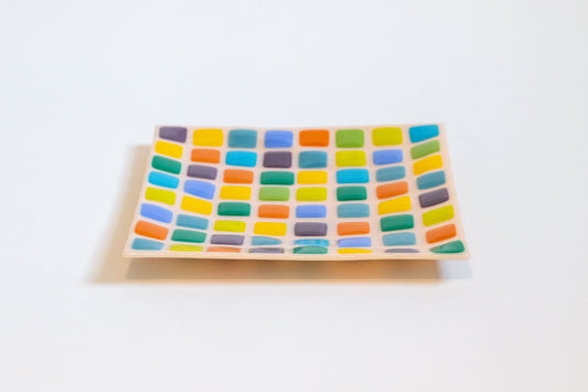 Pink fused glass plate with colorful squares pattern