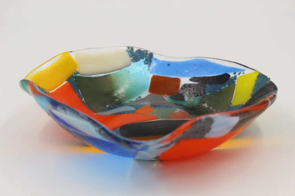 A colorful hand decorated multi-colored glass bowl with squares of orange yellow white blue red