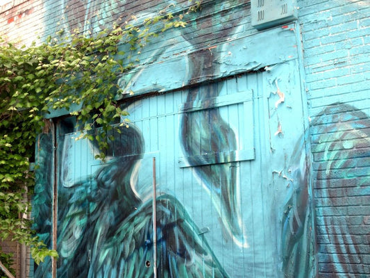 Photograph of blue crane mural covered by ivy