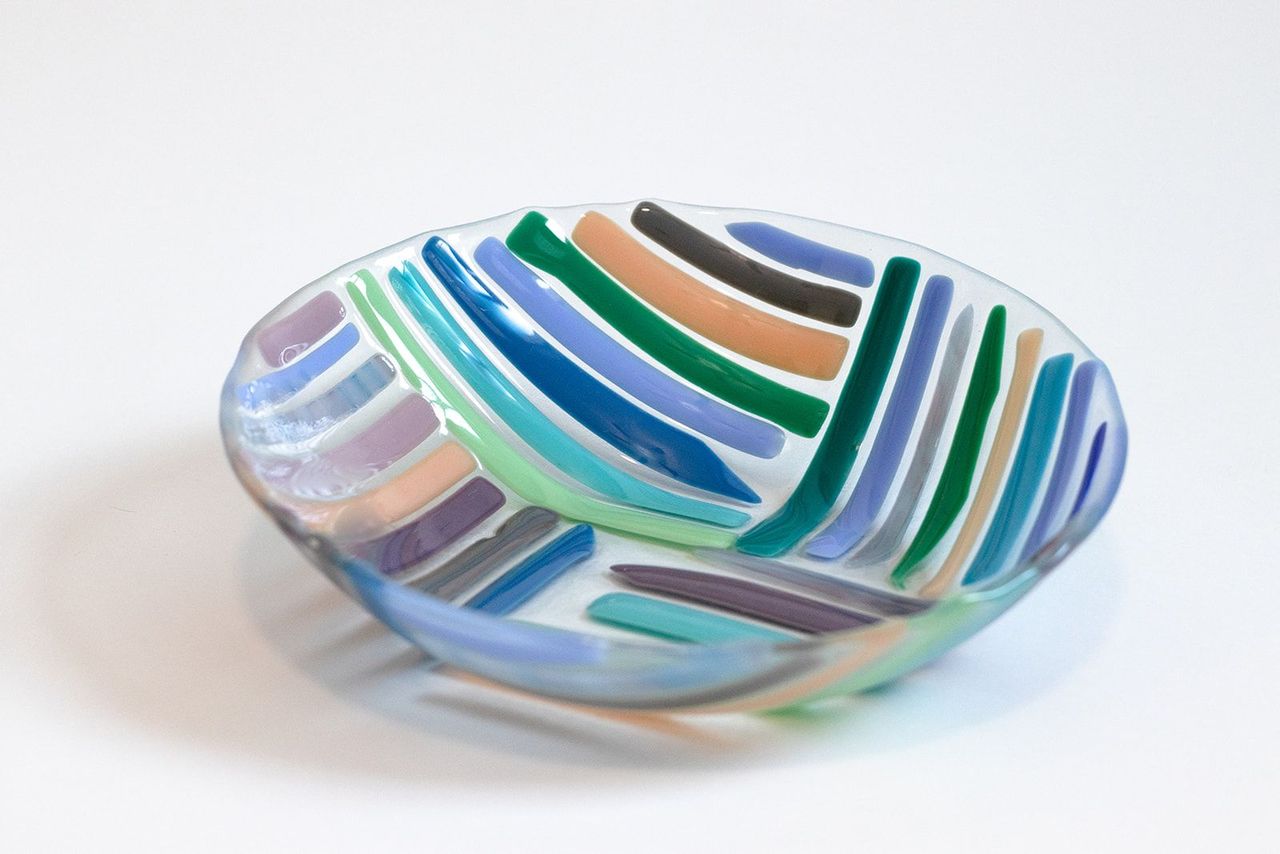 Circular Glass bowl with blues, greens, pruple, and beige lines perpendicular to each other in each coordinate