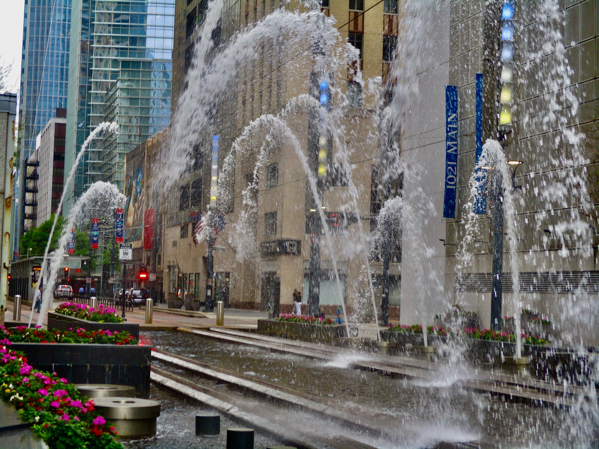 Photography of fountains spurting water in arches across railroad tracks