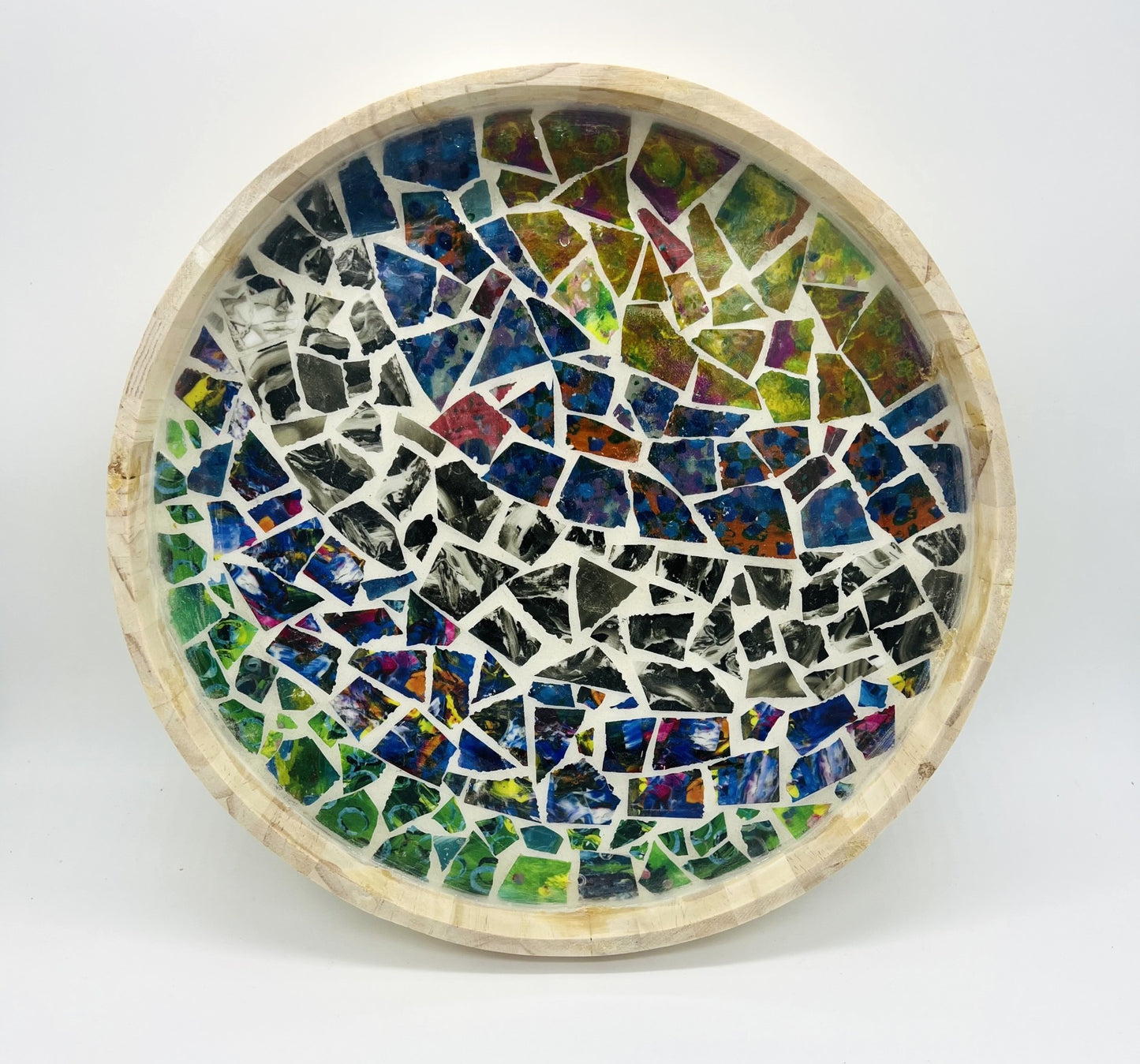 round wooden tray filled with broken mosaic tiles. pattern inside is of radiating curved lines of differing patterns