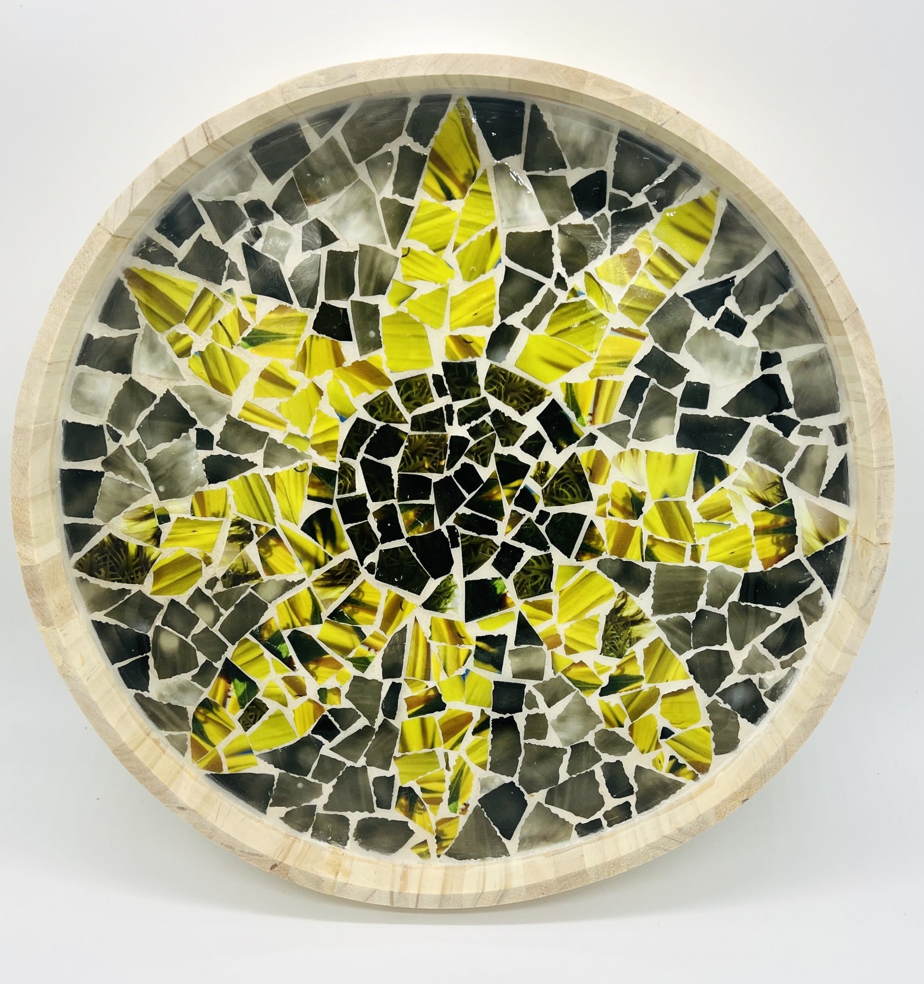 round wooden tray filled with broken mosaic tiles. pattern inside is of a yellow flower against a gray background