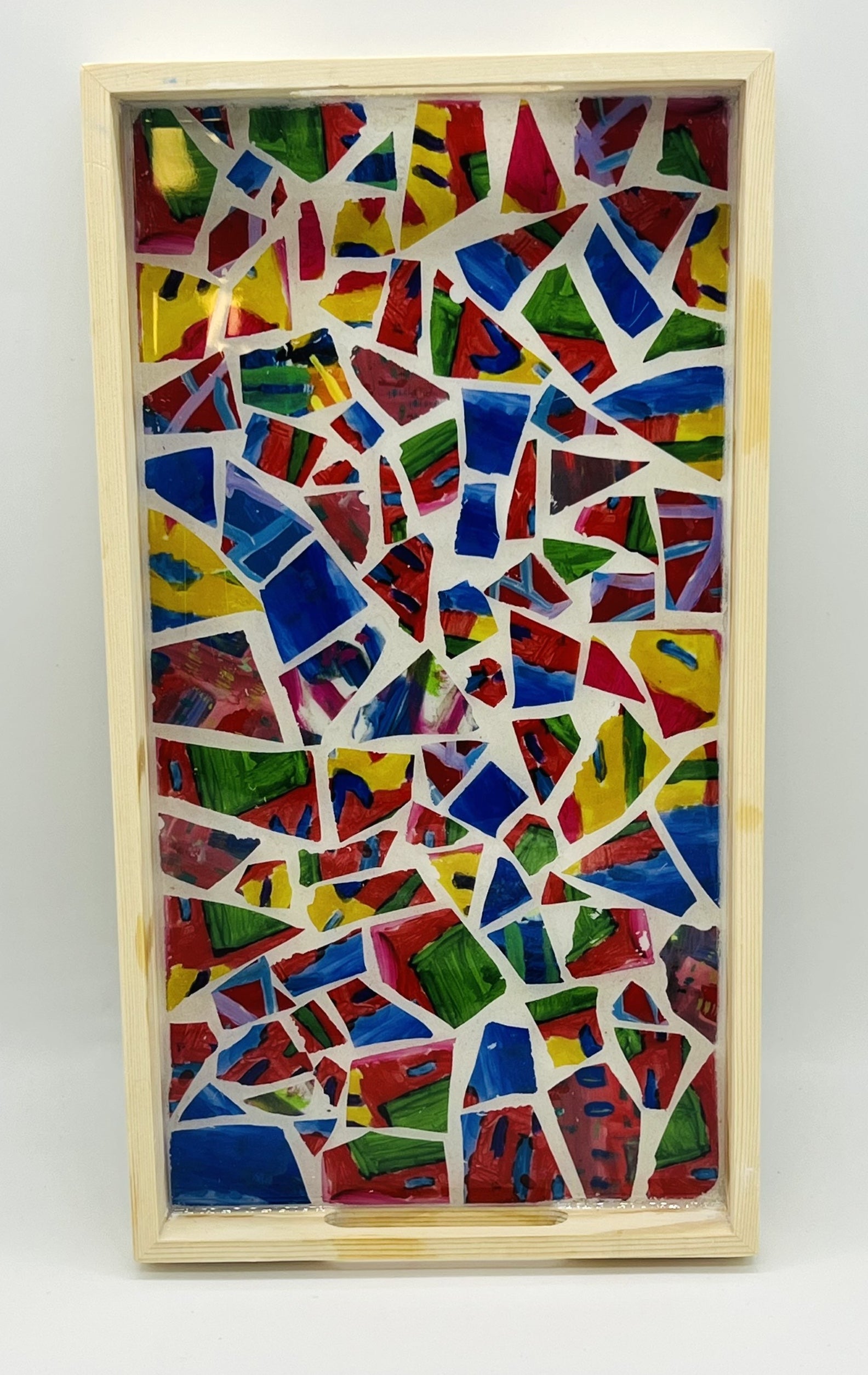 rectangular wooden tray filled with broken mosaic tiles of reds, blue, yellow, and green