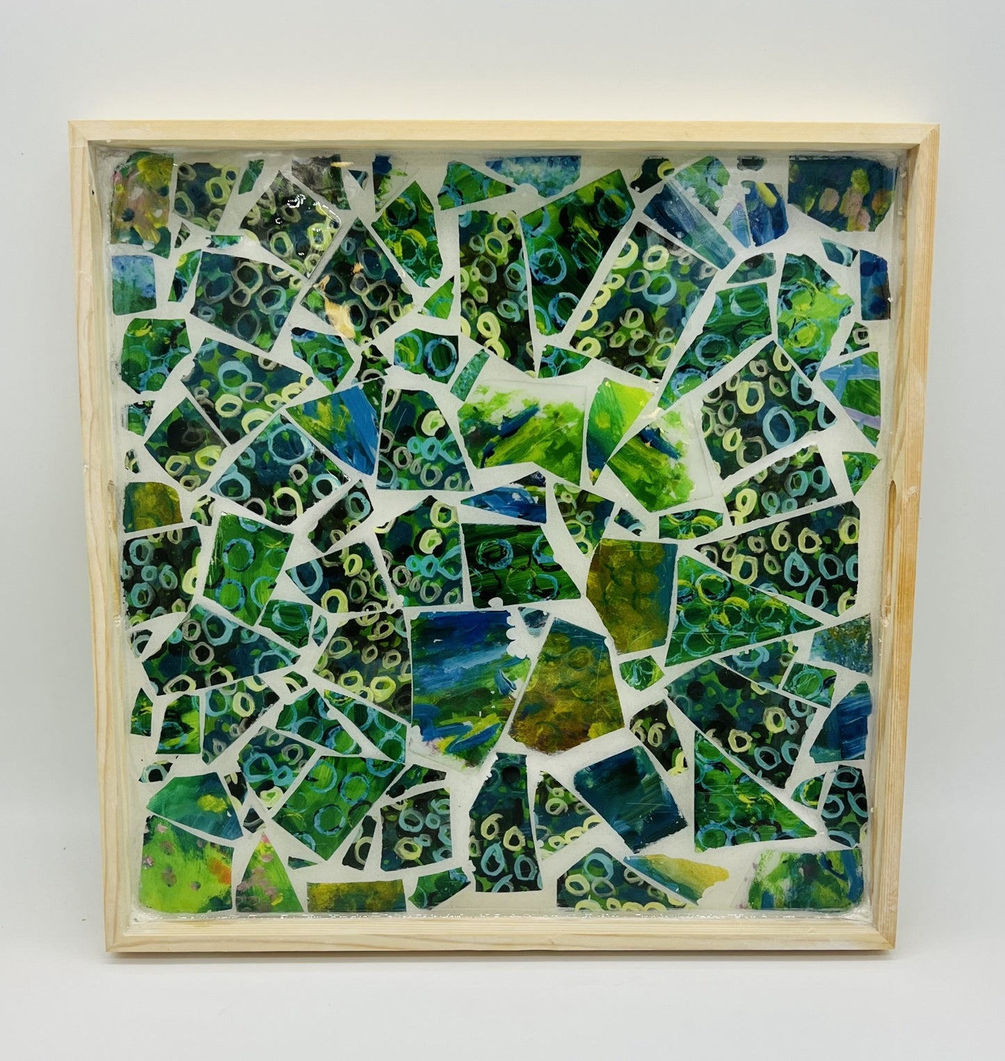 square wooden tray filled with broken mosaic tiles of greens