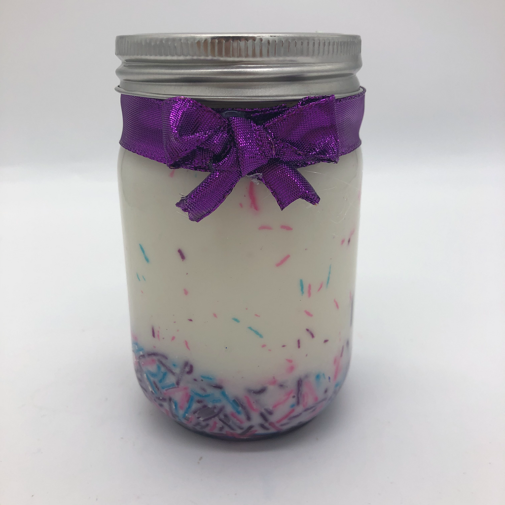 Canning jar with a white candle inside, pink, blue and purple candy sprinkles decorating the sides.  Purple metallic bow on the outside.