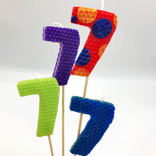 Large beeswax candles of the number 7 in lime green, purple, red and blue