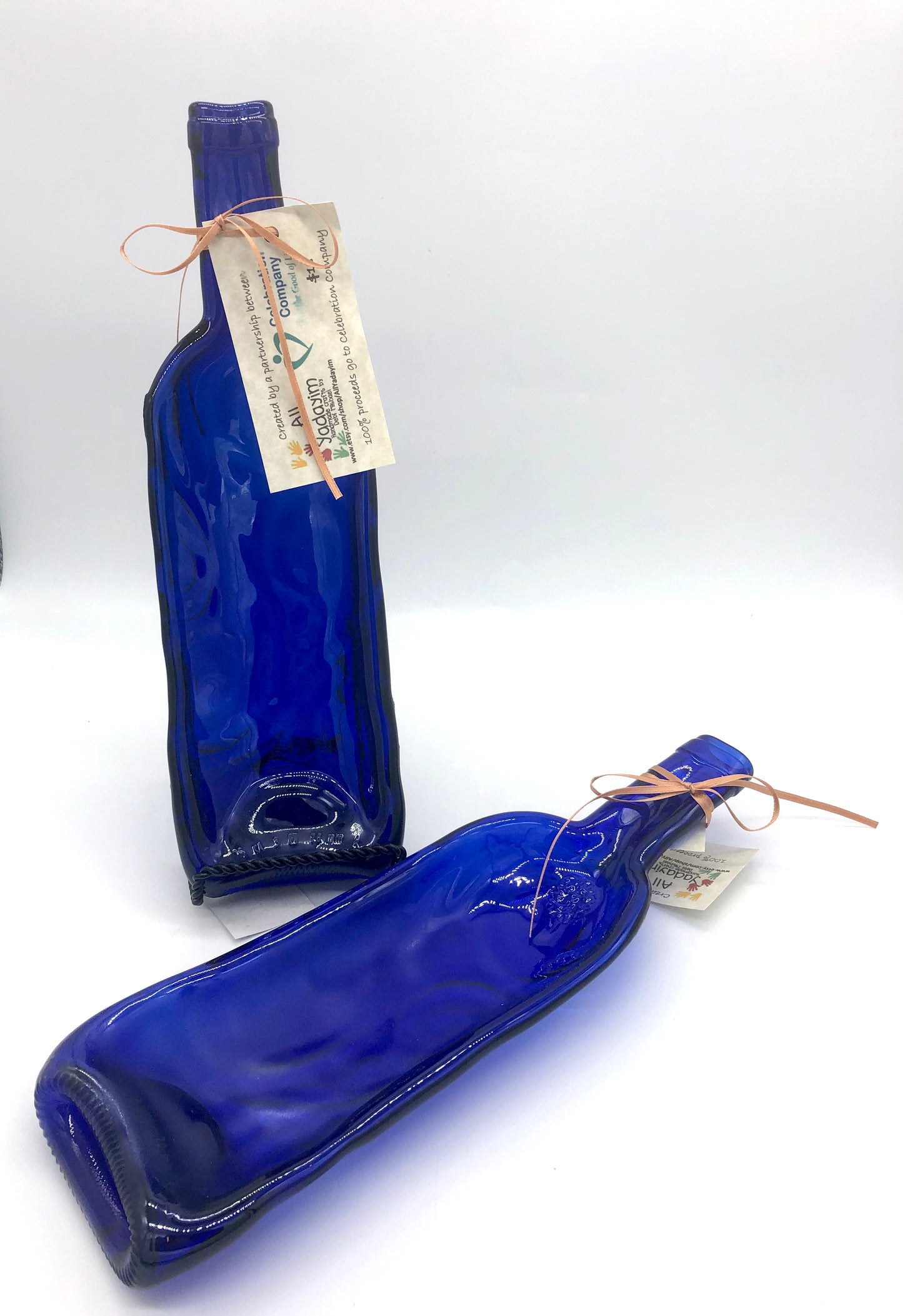 Two blue wine bottles that have been melted down and flattened