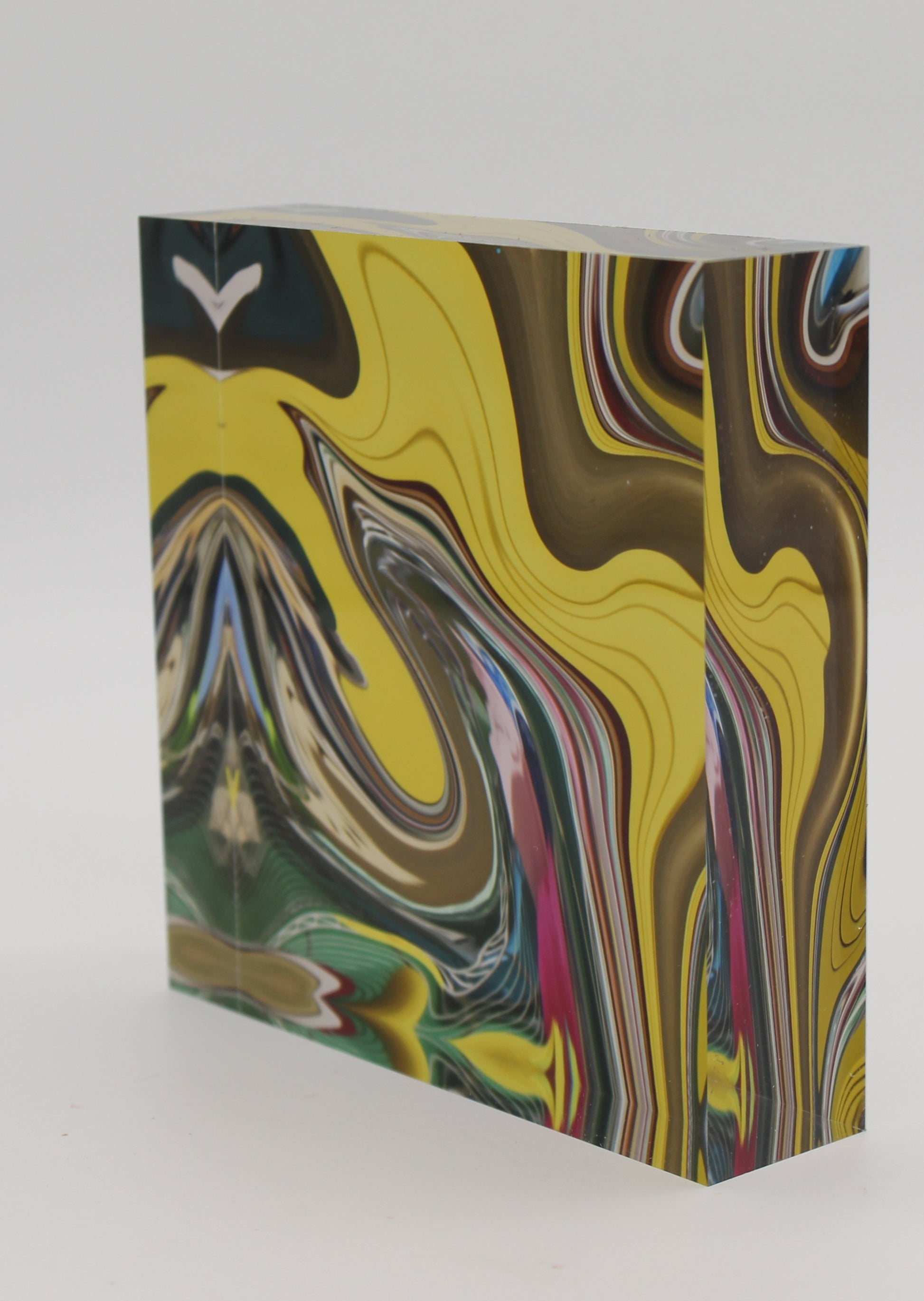 Tilted view of Acrylic block with swirling design of yellow, gold, green, pink swirl