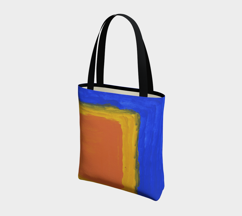 Tote bag with black double straps with blue background and large yellow and orange square in lower right hand corner