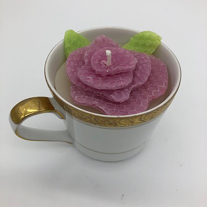 White teacup with gold edging with a pink flower inside