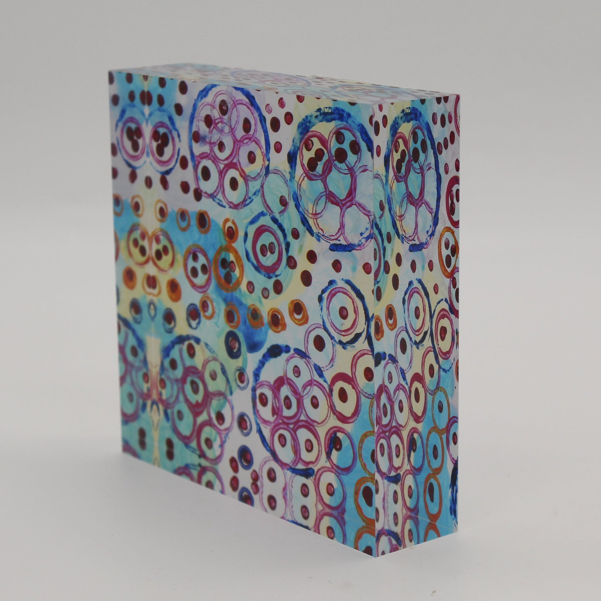 Tilted view of Acrylic block picture of blue, pink, and orange circles with maroon dots