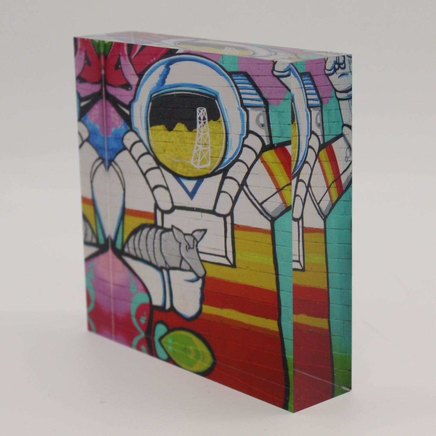 Tilted view of Acrylic block depicting astronaut holding an armadillo with an oil rig over face shield on the helmet