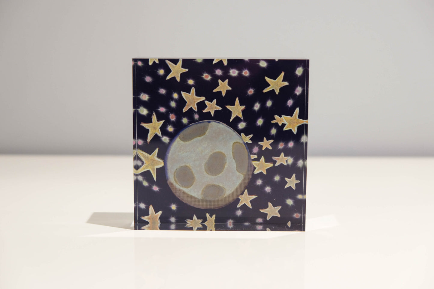 Front view of Acrylic block depicting outer space with a blue background and golden stars with Earth in the center