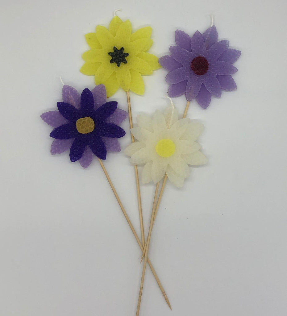 Four large beeswax flower candles in purple, yellow and white
