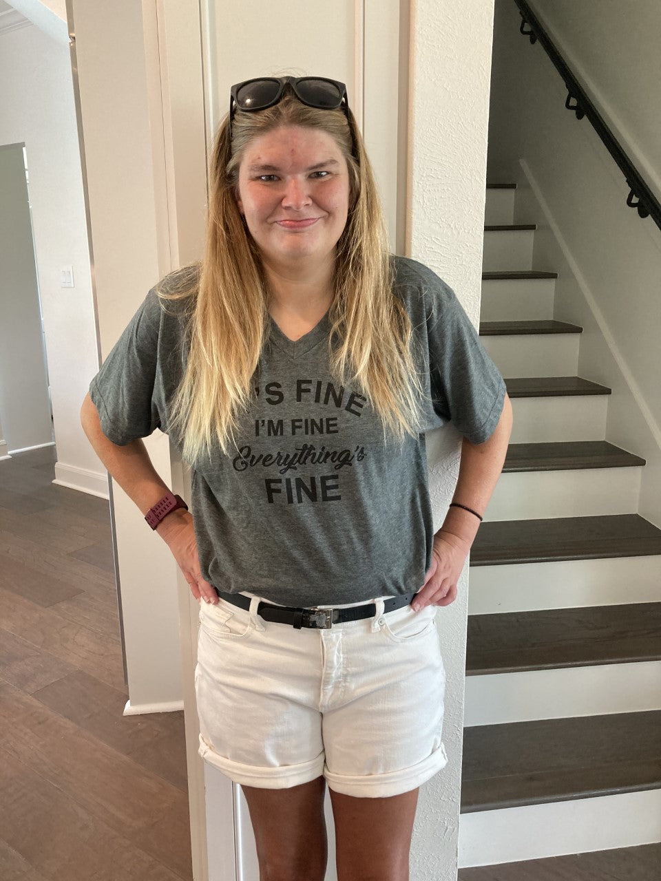 Young woman with blond hair wearing a gray t-shirt that says It's Fine, I'm Fine, Everything's Fine