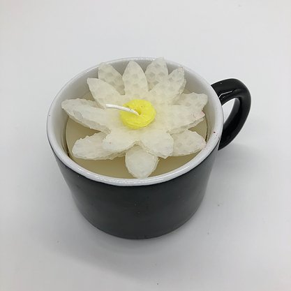 Black coffee mug with a white flower candle inside