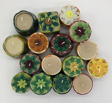 Pottery votives with hand poured candles, some of which are flower shapes