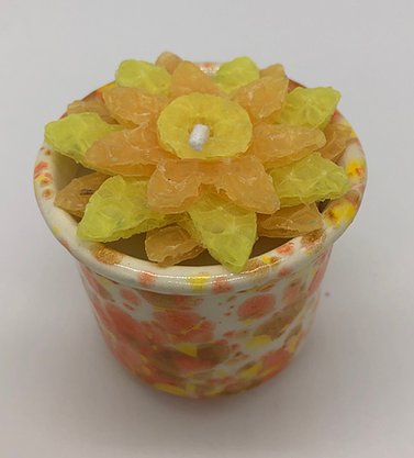 White, orange and yellow pottery votive with a yellow flower candle