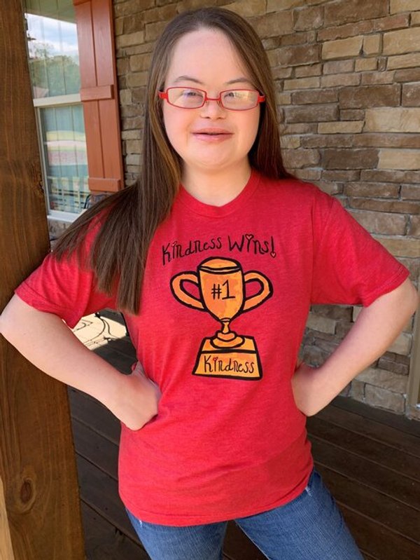 Young woman wearing red tshirt with black Kindness wins slogan above a trophy depicting a #1 and kindness on it