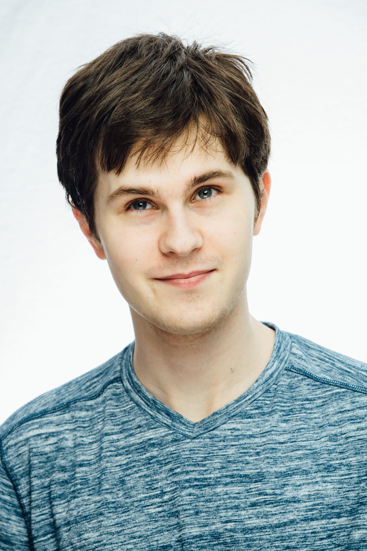 Smiling young man with brown hair and light blue tshirt