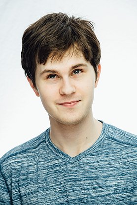  Smiling young man with brown hair and light blue tshirt
