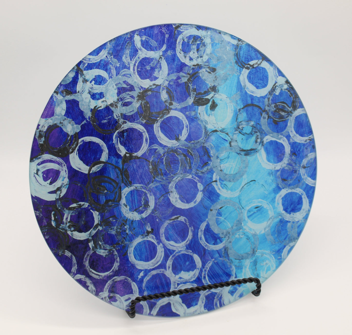 Circular glass cutting board depicting gradient blue background with white and black circles overlaid
