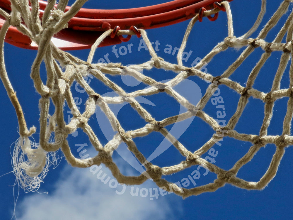 Close up view of white basketball netting and red basketball rim against blue sky