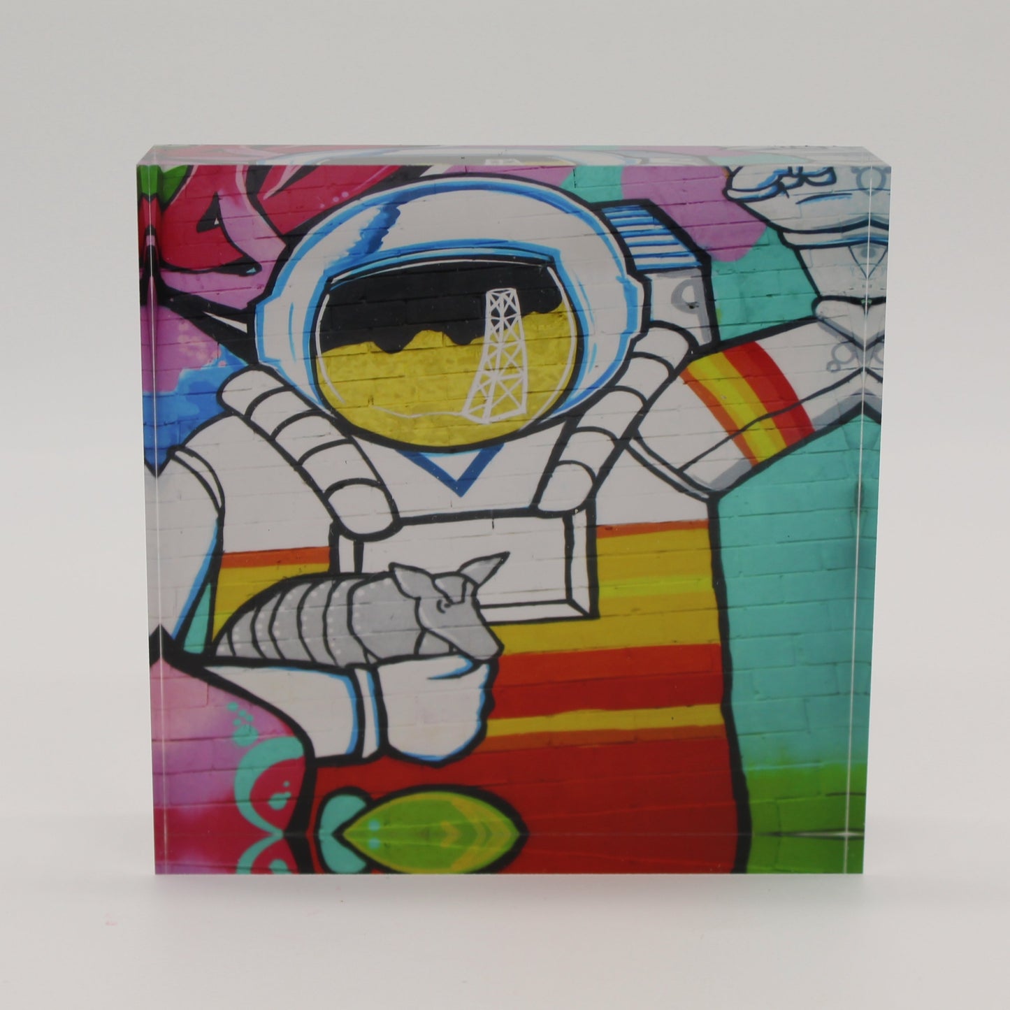 Acrylic block depicting astronaut holding an armadillo with an oil rig over face shield on the helmet
