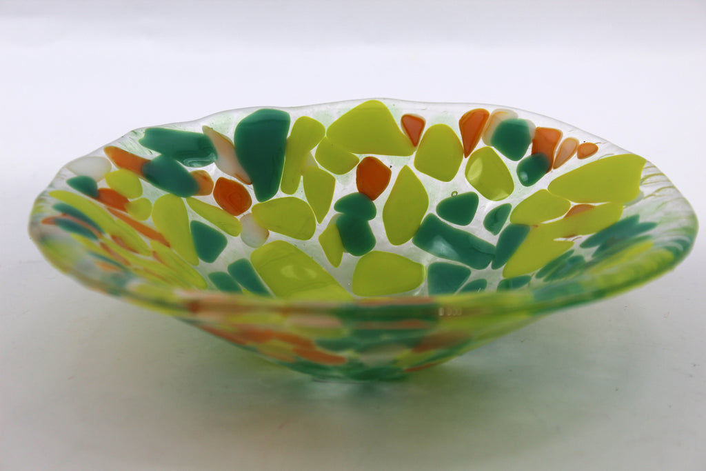 This photo is of a glass bowl with dark green, yellow, and orange irregular/abstract shapes.