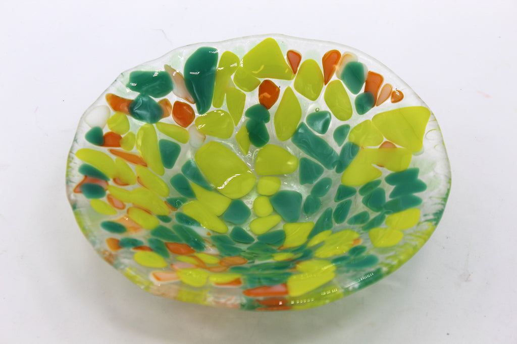 This photo is of a glass bowl with dark green, yellow, and orange irregular/abstract shapes. 